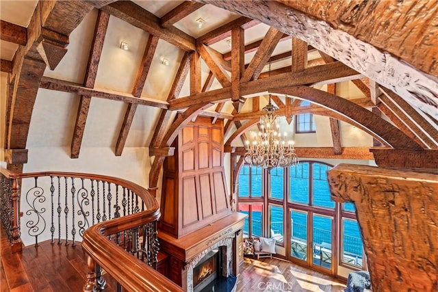 interior space with a fireplace, beam ceiling, wood-type flooring, an inviting chandelier, and a water view