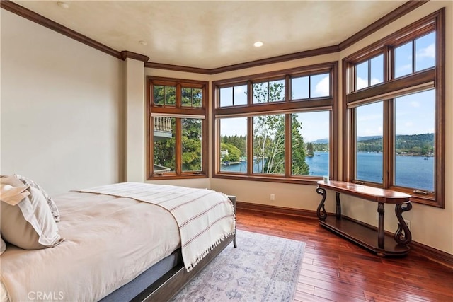 bedroom featuring dark wood-type flooring, ornamental molding, and a water view