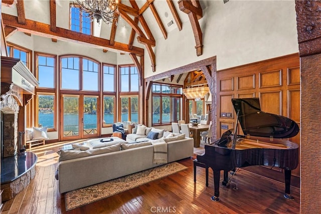 living room featuring an inviting chandelier, wood-type flooring, high vaulted ceiling, a water view, and beamed ceiling