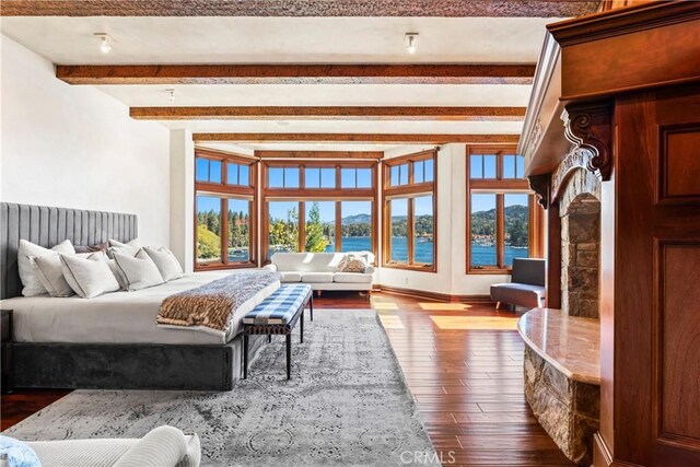 bedroom with a water view, beamed ceiling, and hardwood / wood-style floors