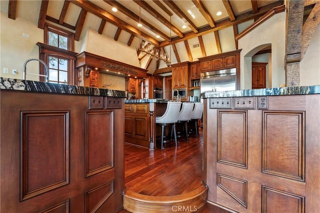 kitchen with high vaulted ceiling, dark hardwood / wood-style flooring, a center island, and built in appliances