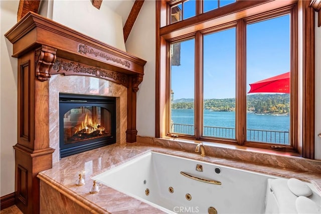 bathroom with a premium fireplace, a bathing tub, and a water view