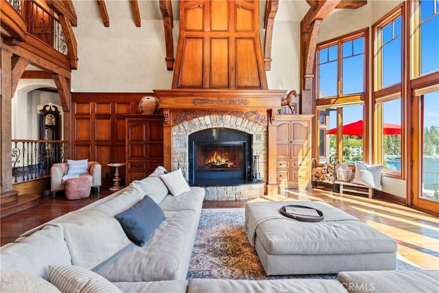 living room with beam ceiling, a towering ceiling, and a fireplace