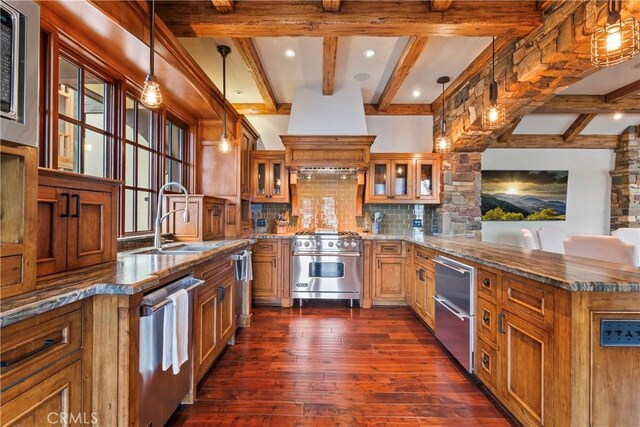 kitchen featuring dark stone countertops, pendant lighting, sink, stainless steel appliances, and dark hardwood / wood-style flooring