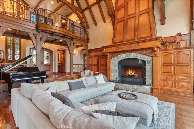 living room with high vaulted ceiling, hardwood / wood-style flooring, beam ceiling, and a fireplace