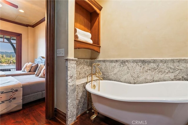 bathroom featuring a tub to relax in, crown molding, and hardwood / wood-style floors