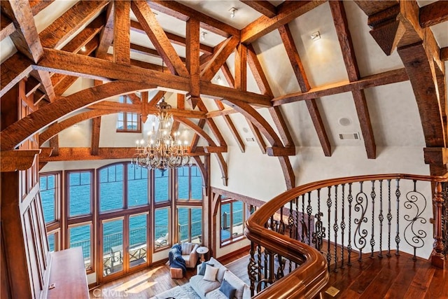 sunroom with a chandelier, a water view, and lofted ceiling with beams