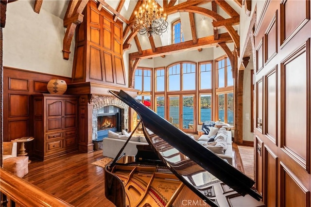 interior space with wood-type flooring, an inviting chandelier, a water view, high vaulted ceiling, and beam ceiling