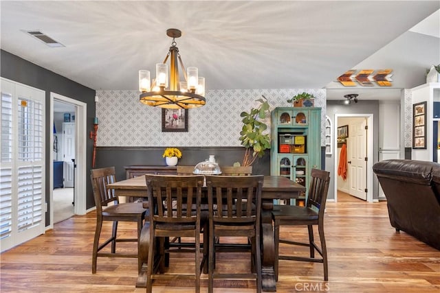 dining area with light wood-type flooring, a wealth of natural light, and a notable chandelier