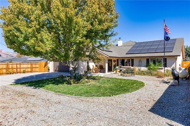 view of front of house with solar panels, a garage, and a patio area