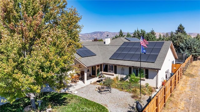 back of property with a mountain view, solar panels, and a patio area