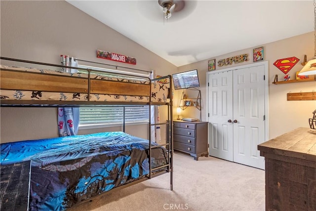 bedroom with light carpet, vaulted ceiling, a closet, and ceiling fan