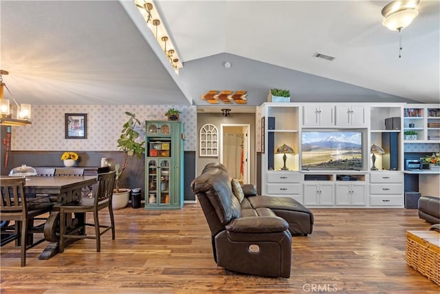 living room featuring track lighting, lofted ceiling, and hardwood / wood-style flooring