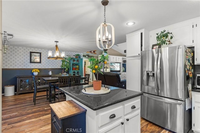 kitchen with dark wood-type flooring, dark stone countertops, a kitchen island, white cabinetry, and stainless steel appliances