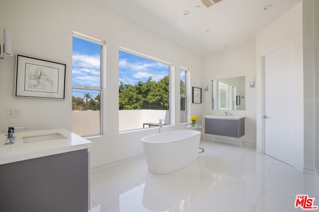 bathroom with tile patterned floors, a bathing tub, and vanity