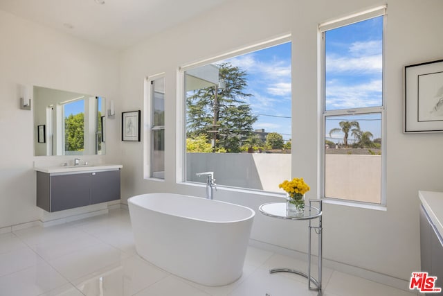 bathroom with tile patterned floors, a tub, and vanity