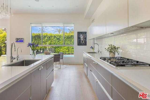 kitchen with stainless steel gas stovetop, hanging light fixtures, a healthy amount of sunlight, and sink