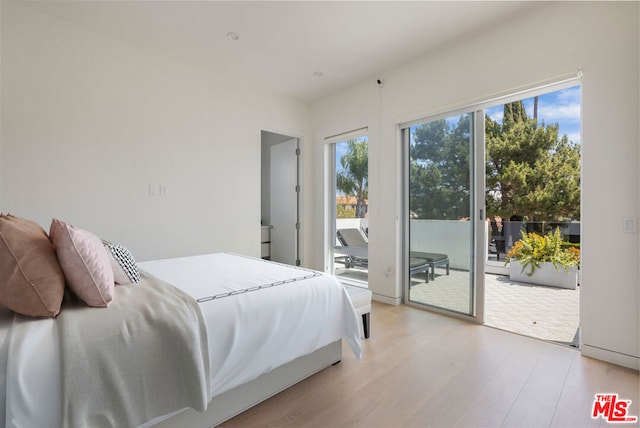 bedroom featuring light hardwood / wood-style flooring, access to outside, and multiple windows