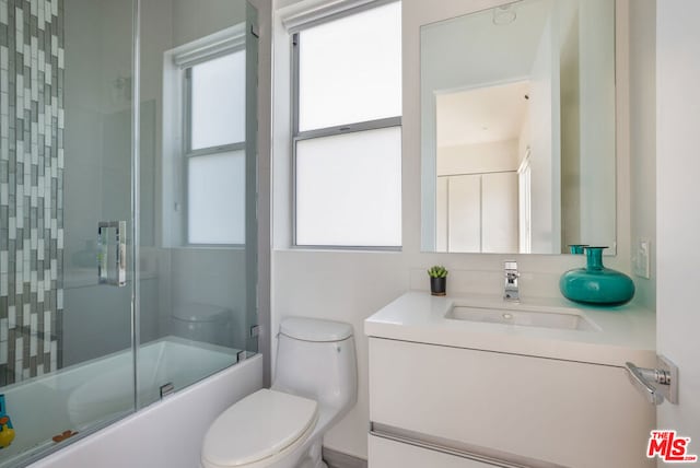 full bathroom featuring vanity, toilet, and bath / shower combo with glass door