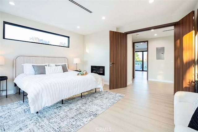 bedroom with electric panel and light hardwood / wood-style floors