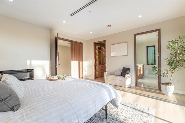 bedroom featuring ensuite bathroom and wood-type flooring