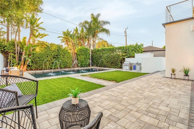 view of patio / terrace featuring a fenced in pool, pool water feature, and exterior kitchen