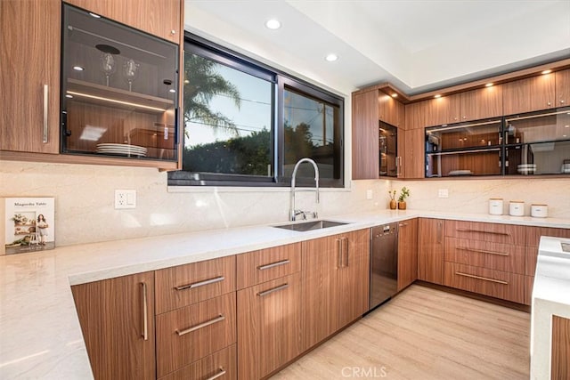 kitchen with stove, light wood-type flooring, tasteful backsplash, sink, and dishwasher