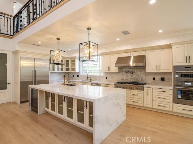 kitchen with a center island with sink, light wood-type flooring, sink, and stainless steel appliances