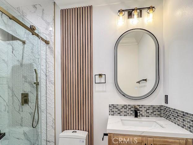 bathroom featuring ornamental molding, vanity, a shower with shower door, and toilet