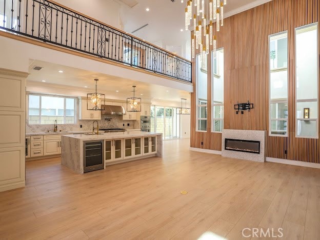 interior space featuring a towering ceiling, beverage cooler, and light wood-type flooring