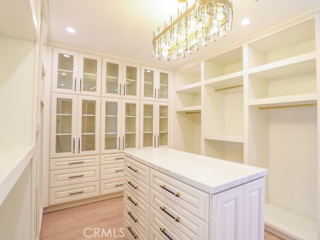 walk in closet with a chandelier and light hardwood / wood-style floors