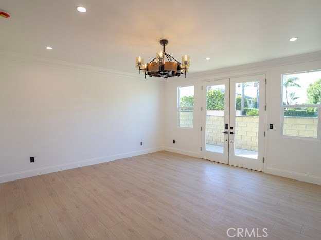 interior space with ornamental molding, french doors, an inviting chandelier, and light hardwood / wood-style flooring