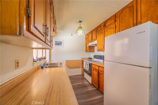 kitchen with pendant lighting, sink, white appliances, and dark hardwood / wood-style flooring