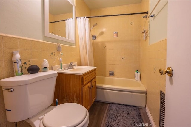 full bathroom featuring toilet, hardwood / wood-style flooring, shower / bath combo with shower curtain, tile walls, and vanity