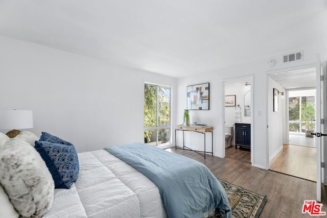 bedroom featuring multiple windows, hardwood / wood-style flooring, and ensuite bath