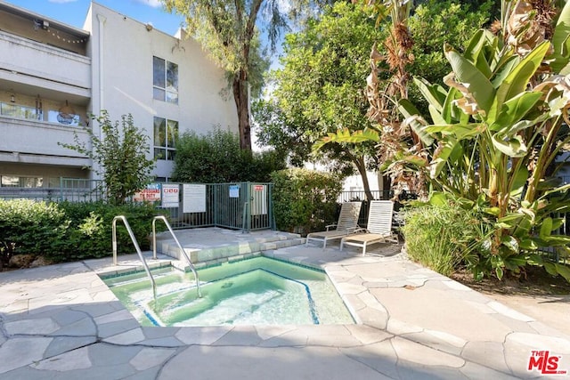 view of pool with a hot tub