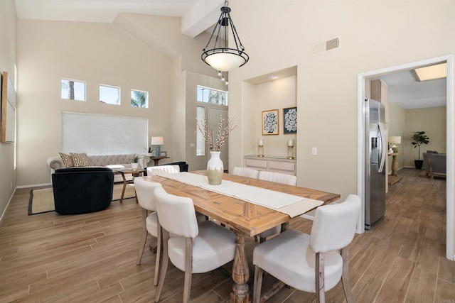 dining area featuring light hardwood / wood-style flooring and high vaulted ceiling