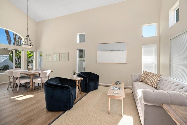 living room with a healthy amount of sunlight, high vaulted ceiling, and light hardwood / wood-style floors