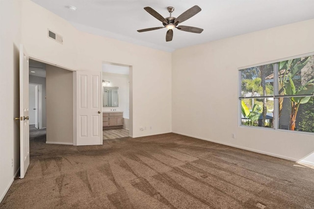 unfurnished bedroom with ensuite bath, ceiling fan, and dark carpet