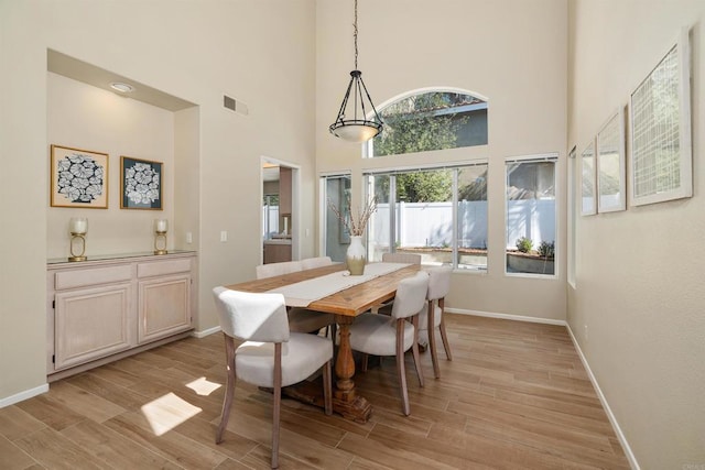 dining area featuring a towering ceiling and light hardwood / wood-style floors