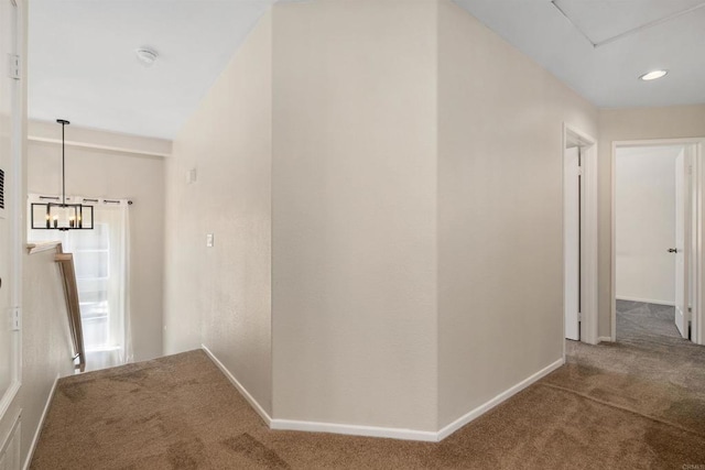 hallway with carpet flooring and an inviting chandelier