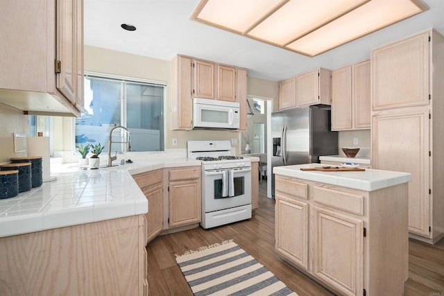 kitchen with tile countertops, a center island, white appliances, and light wood-type flooring