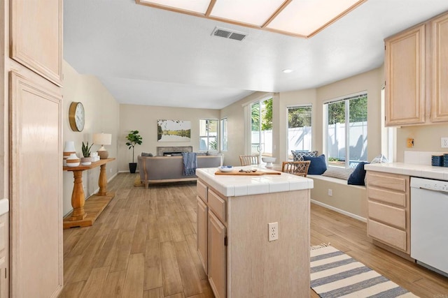 kitchen featuring tile countertops, dishwasher, light brown cabinets, and light hardwood / wood-style flooring