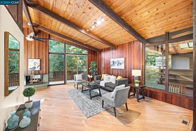 living room with ceiling fan, wooden ceiling, light hardwood / wood-style flooring, lofted ceiling with beams, and wooden walls