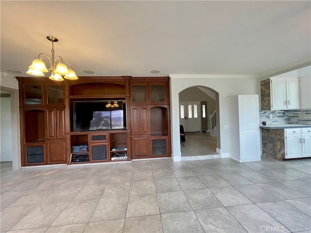 unfurnished living room with an inviting chandelier, ornamental molding, and light tile patterned flooring