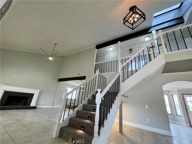 staircase featuring ornamental molding, ceiling fan, a towering ceiling, and tile patterned floors