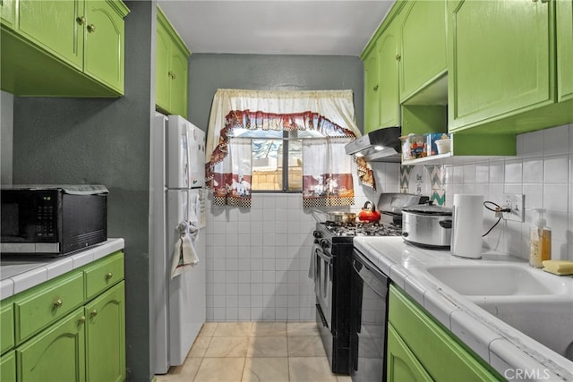 kitchen featuring black appliances, tile counters, green cabinets, and light tile patterned floors