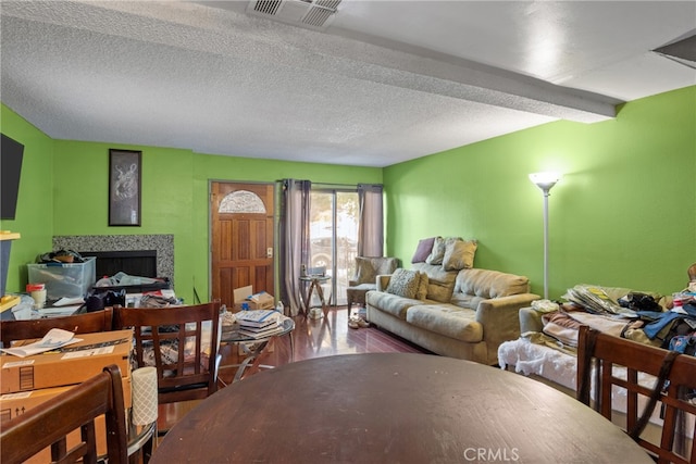 living room featuring beamed ceiling, a textured ceiling, a fireplace, and hardwood / wood-style flooring