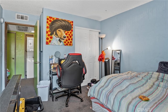 carpeted bedroom with a textured ceiling, a closet, and stacked washing maching and dryer