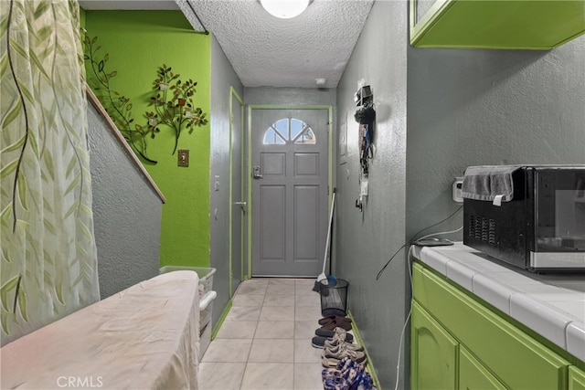 doorway to outside with a textured ceiling and light tile patterned floors